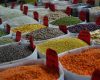 Bags of vibrant grains and spices on display in a bustling market setting.